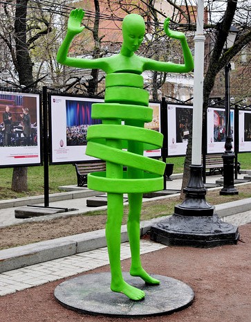 Пластикова сучасна скульптура зеленого кольору, людина в спіралі.